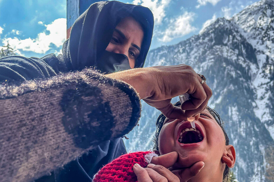 A health worker administers polio drops to a child during a door-to-door vaccination campaign amidst heavy snow in the Bakwali-Surgan area of Azad Jammu Kashmir's Neelum Valley, on February 4, 2025. (AFP